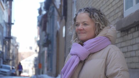 Une femme sourit dans une rue du Vieux-Québec, l'hiver. 