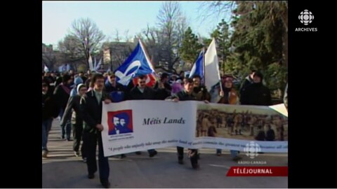 Groupe de Métis qui marchent dans une rue en tenant une banderole avec l'inscription « Métis Lands ».