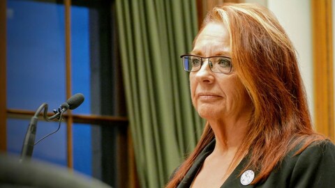 Une femme aux cheveux longs roux se tient devant un micro. Une femme aux cheveux longs roux se tient devant un micro.