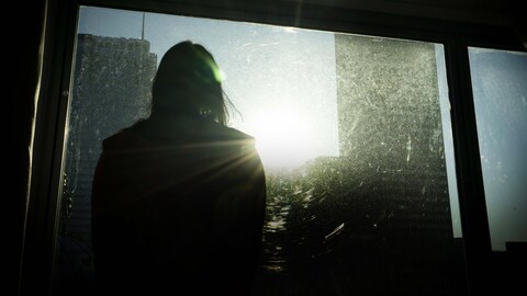 Une femme regarde par la fenêtre d'un hôtel.