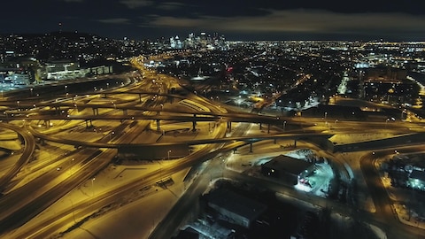 Une vue aérienne et de nuit de l'échangeur Turcot, avec au fond le centre-ville de Montréal.