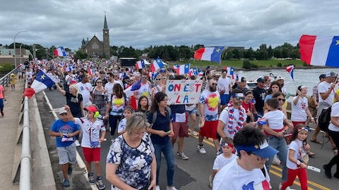 A gathering of people sporting Acadian shirts and flags.
