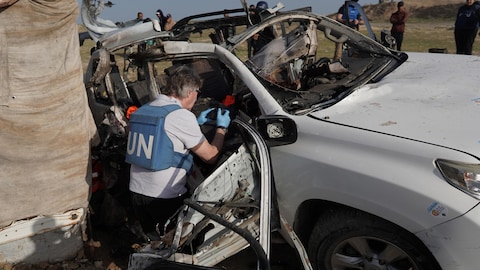 Un inspector de la ONU toma fotos de los restos de un coche.