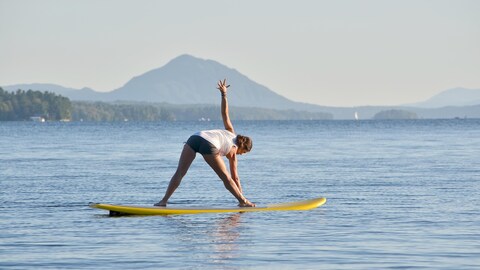 Une femme fait du yoga sur une planche à pagaie. Une femme fait du yoga sur une planche à pagaie.