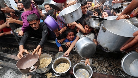 Des femmes, des hommes et des enfants tendent des sauts et des casseroles dans la cohue.