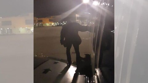 Un homme se tient debout sur l'aile d'un avion posé dans un aéroport. 