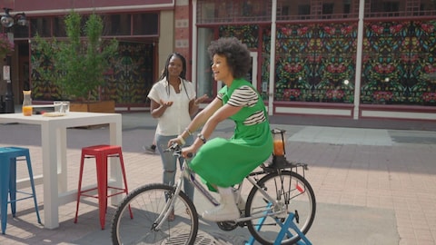 Marieme Ndiaye pédale sur un vélo auquel un mélangeur rempli de smoothie est accroché.