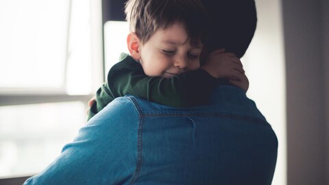 Un père prend son fils dans ses bras