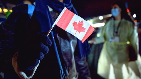 A newly-landed refugee waves a Canadian flag outside St. John's International Airport on October 26, 2021.