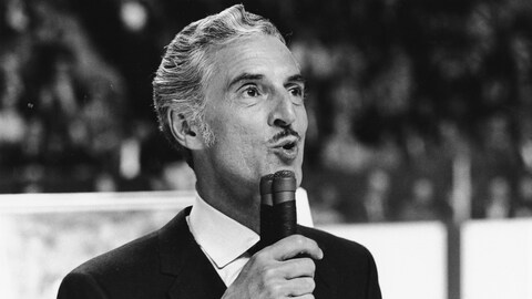 René Lecavalier, au milieu de la glace et micro à la main, faisant une présentation.