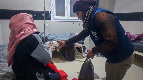 Un bénévole distribue des denrées à une victime du séisme en Syrie.
