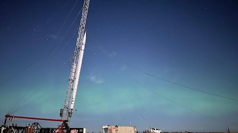 A rocket standing upright in the middle of a plain.