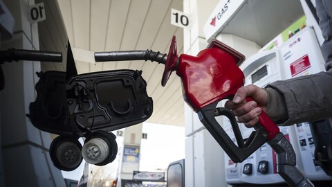 Une femme fait le plein à une station-service.