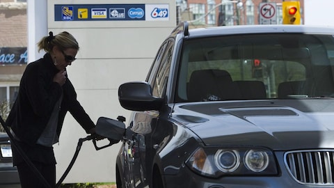 Una mujer carga gasolina a su auto en una estación de servicio.