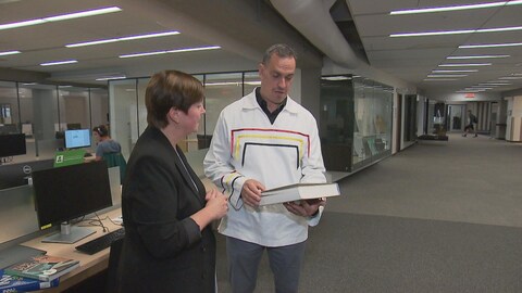 Susanne Brillant et Yves Siouï tiennent un livre. Ils sont dans la bibliothèque.