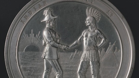 Une médaille sur laquelle sont gravés un chef autochtone et un officier britannique se serrant la main.