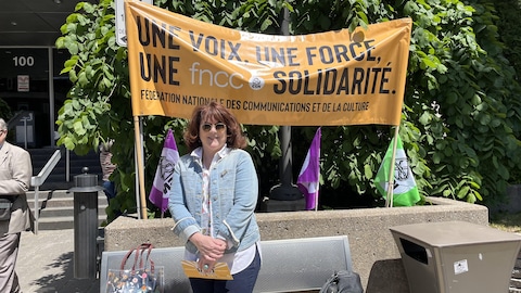 Annick Charette, présidente de la FNCC–CSN, devant une banderole