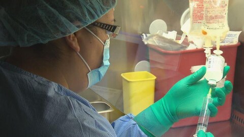 Une infirmière injecte un médicament au soluté.