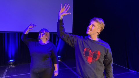 Les deux artistes ont un bras dans les airs et leur main est complètement ouverte.
