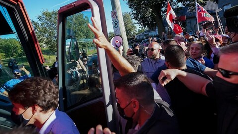 RCMP security officers put their hands up to protect Liberal Leader Justin Trudeau from tossed gravel while leaving a campaign stop in London Ont., on September 6, 2021.