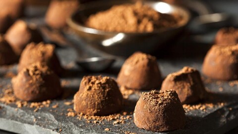 Des truffes au chocolat disposées sur un plateau d'ardoise