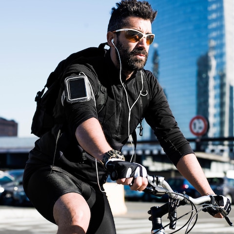 Un cycliste circule alors qu'il porte des écouteurs. Il porte aussi des verres fumés et semble se trouver en milieu urbain. Un cycliste circule alors qu'il porte des écouteurs. Il porte aussi des verres fumés et semble se trouver en milieu urbain.