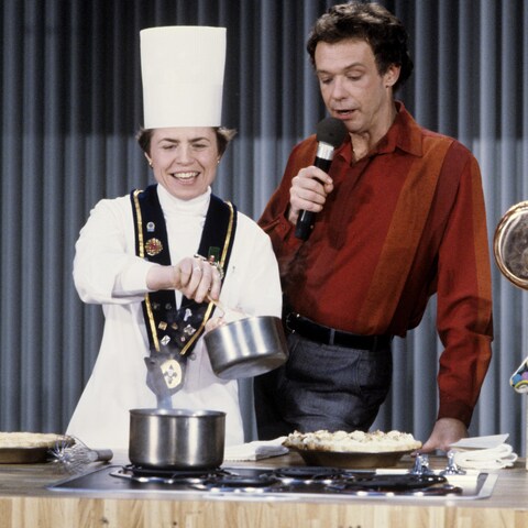 Sœur Angèle, qui porte la toque de chef, prépare une recette en compagnie de Jacques Boulanger.
Sœur Angèle, qui porte la toque de chef, prépare une recette en compagnie de Jacques Boulanger.