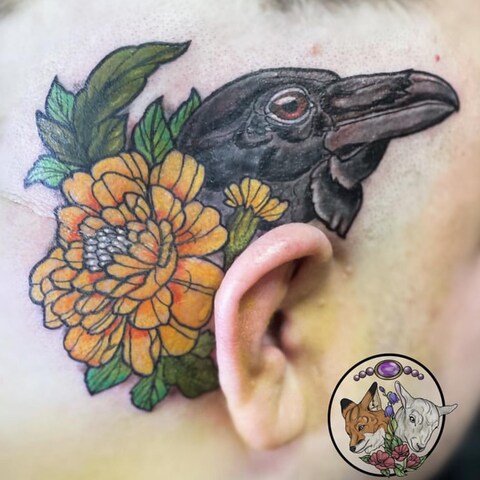 Un tatouage créé par Arielle Racette représentant un oiseau caché derrière des fleurs. Le tatouage se trouve sur la tête d'une personne derrière son oreille.