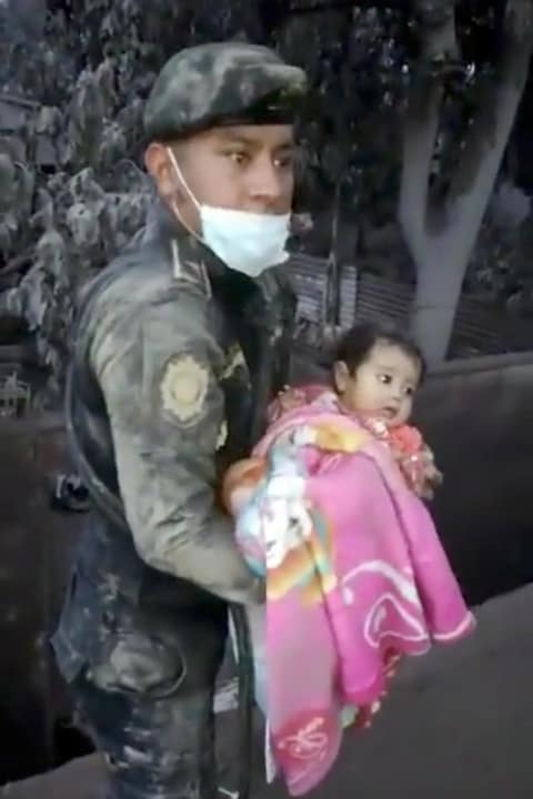Un soldat porte dans ses bras une petite fille qu'il vient de sortir des décombres après l'éruption du volcan de Fuego, à Escuintla, au Guatemala. Un soldat porte dans ses bras une petite fille qu'il vient de sortir des décombres après l'éruption du volcan de Fuego, à Escuintla, au Guatemala.