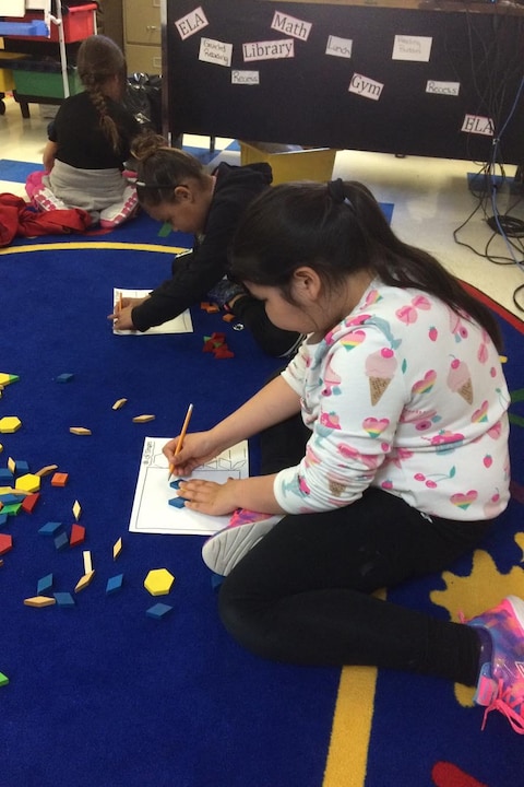 Des enfants dessinent sur un tapis bleu dans leur classe. Des enfants dessinent sur un tapis bleu dans leur classe.