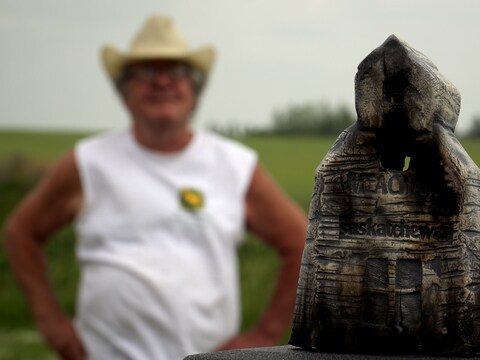 Le céramiste Charley Farrero en arrière-plan. L'oeuvre de l'artiste en avant-plan est une représentation du silo à grain du village de Meacham en Saskatchewan.