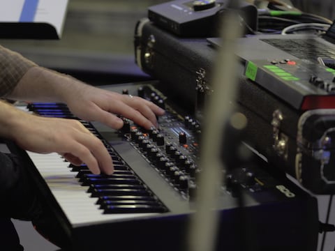 Un musicien joue un piano électrique branché à un ordinateur.