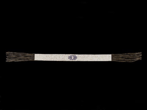La ceinture est fabriquée en perles tubulaires de couleurs mauve et blanche. La ceinture est fabriquée en perles tubulaires de couleurs mauve et blanche.