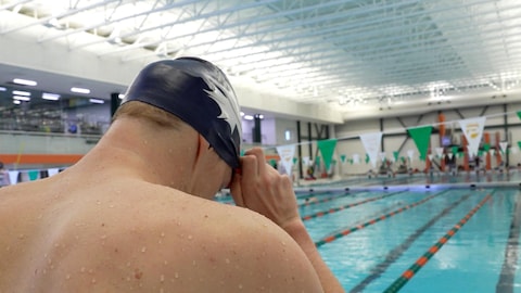 Un nageur met un casque sur sa tête près d’une piscine.