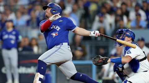 Un jugador de béisbol mira al cielo al terminar su batazo, frente al receptor. 