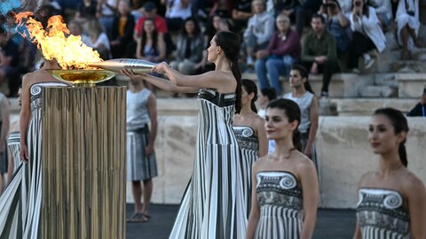 Une femme allume un flambeau à partir d'une vasque au cours d'une cérémonie.