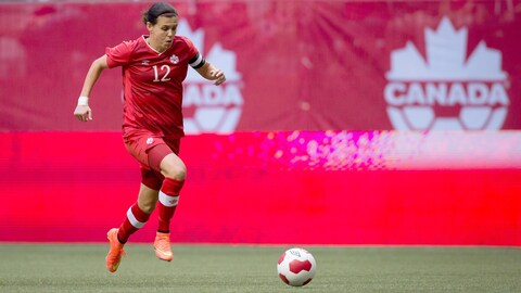 Une joueuse en rouge court avec le ballon.