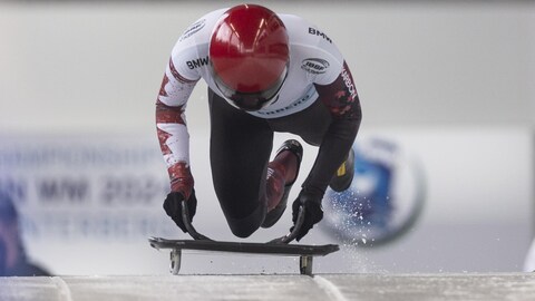 Une athlète de skeleton de face s'élance sur la piste glacée en poussant son engin.