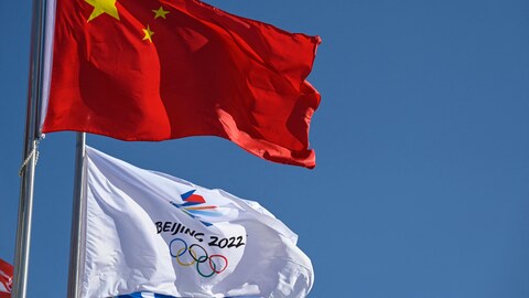 Un drapeau chinois et un autre avec le logo des Jeux de Pékin flottent au vent.