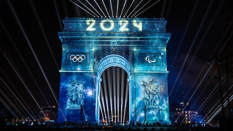L'Arc de triomphe est illuminé dans la nuit parisienne.