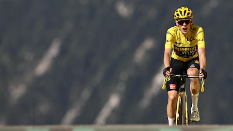 Un cycliste portant un maillot jaune arrive au sommet d'une colline.