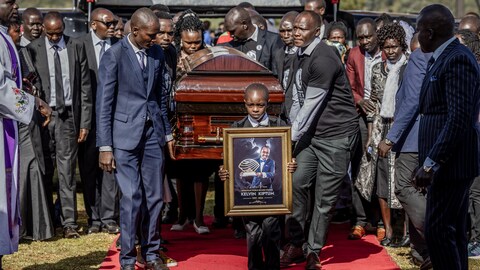 Un jeune porte une toile de l'athlète devant le cercueil.