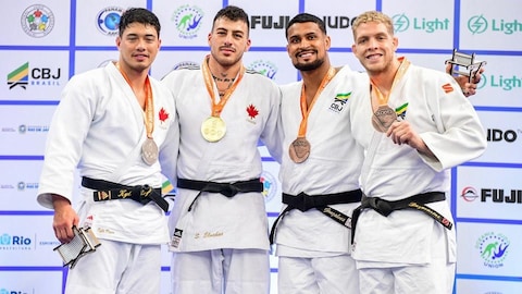 Quatre judokas posent à la caméra avec chacun une médaille.