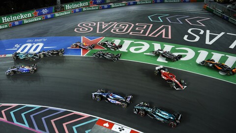 Des monoplaces de F1 roulent sur un circuit illuminé. 