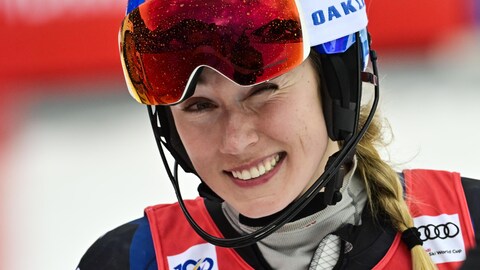 Une skieuse casquée fait un clin d'oeil et sourit pour la photo.