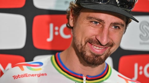 Peter Sagan, dans son maillot de cycliste blanc avec un col arc-en-ciel de champion du monde, répond à des questions pendant un point de presse.