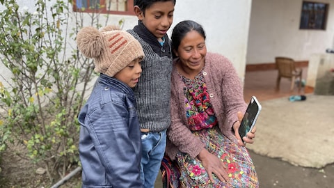 Deux enfants, ainsi que leur mère, parlent à leur père par vidéoconférence.