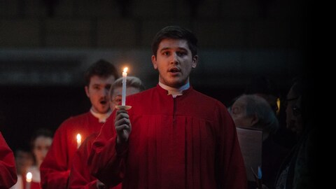 Quelques membres du chœur de l'église St.Andrew et St.Paul, vêtus d'une toge rouge et chandelle à la main, chantent.  