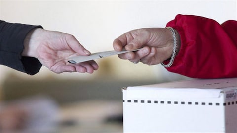 Début du vote par anticipation aux élections provinciales en Colombie-Britannique, un bulletin de vote et deux mains.