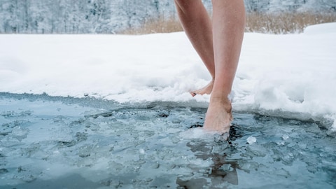 Une femme trempe son pied dans de l'eau glacée.